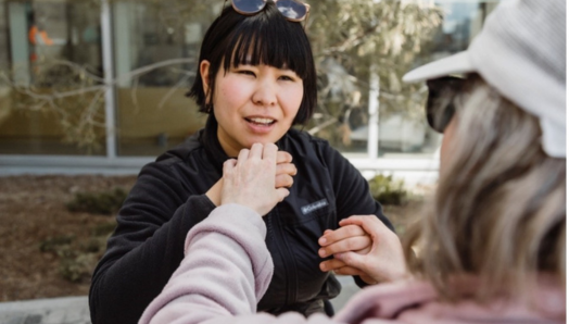 Un intervenant utilise la langue des signes américaine (ASL) tactile, qui consiste à placer délicatement les mains sur le dessus de la personne qui signe pour sentir les signes lorsqu’ils sont faits pour communiquer avec le client.