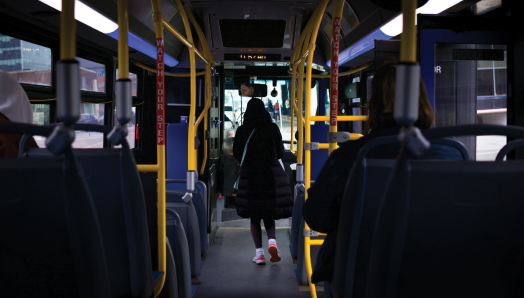 L’intérieur d’un autobus urbain. L’image est prise de l’arrière de l’autobus, où une personne avance dans l’allée vers la porte avant.