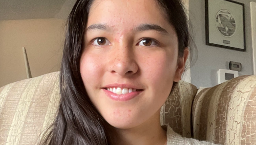 Portrait d'Anna Kim souriante, assise sur un canapé.