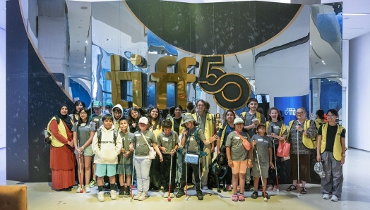 Dans le hall du TIFF Lightbox, un grand groupe de jeunes campeurs et de bénévoles d’INCA posent pour une photo de groupe devant une enseigne géante « TIFF 50 ».