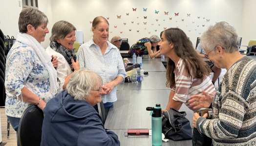 Lyne Dubé, chef de programme en technologie adaptée chez INCA, discute et rit avec cinq participantes.
