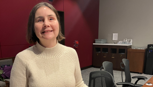 Jen Goulden sourit, debout devant un bureau dans une salle de réunion du Comité sénatorial. Sur le bureau, elle tient son exemplaire en braille du roman « La Communauté de l’Anneau », composé de six volumes épais et lourds. Au sommet de la pile se trouve une version de poche standard du livre, minuscule en comparaison. Ces accessoires ont été utilisés pour illustrer les coûts élevés liés à l’expédition de documents en braille.