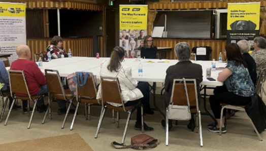 Neuf membres de la communauté sont assis autour d’une table et discutent.